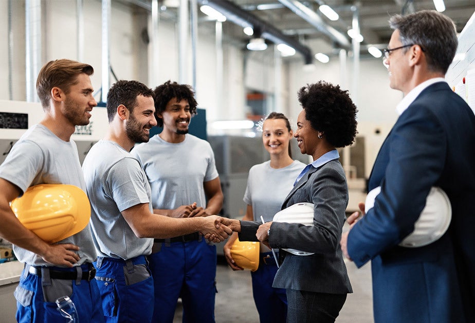 Industrial workers greeting corporate employees in a factory setting