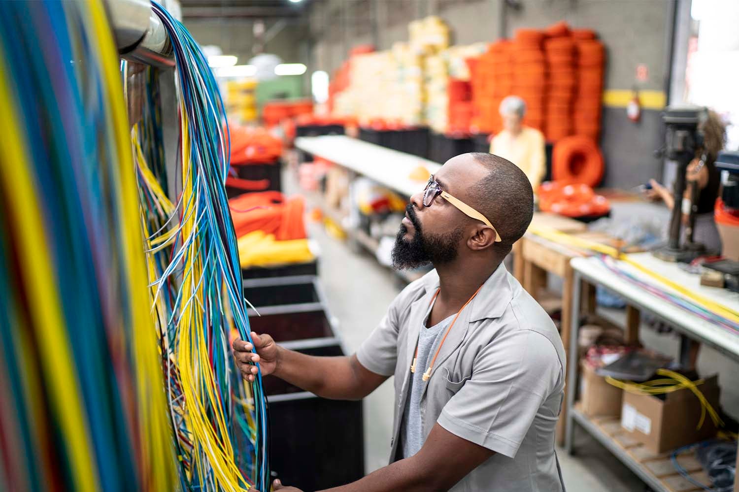Electrical employee examining wires in factory setting