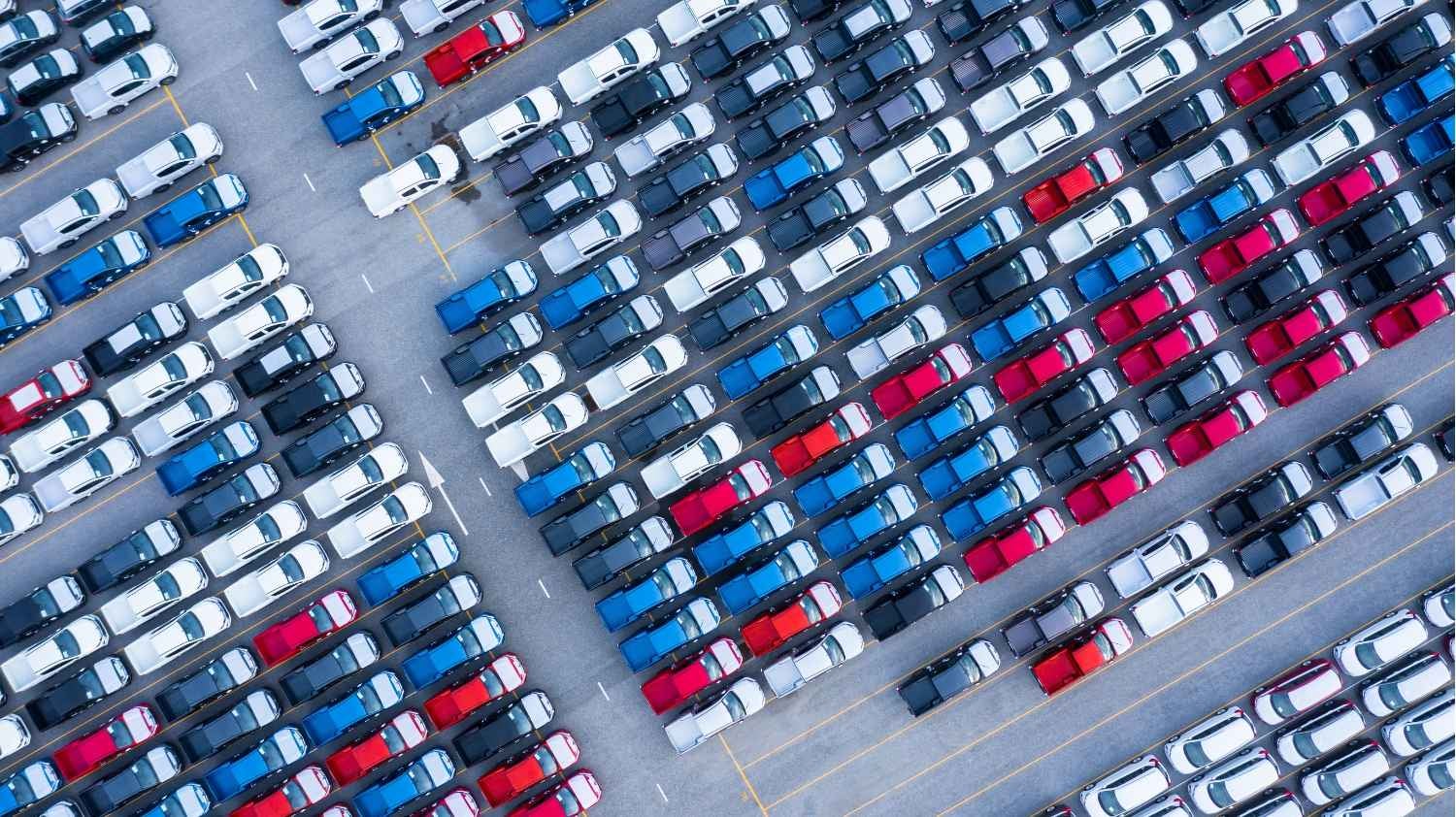 Overhead view of a parking lot with red, white, and black cars