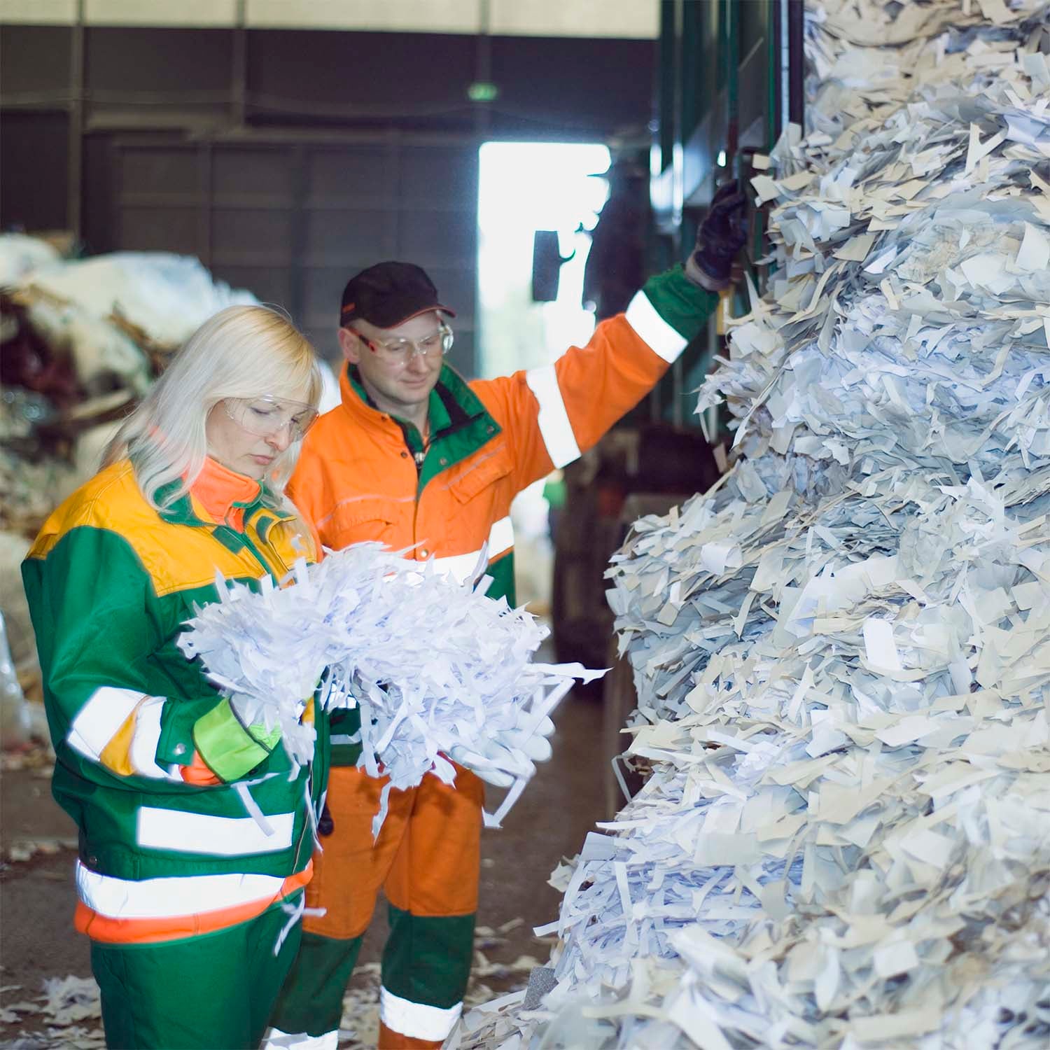 Two industrial employees examining paper scraps in a factory setting