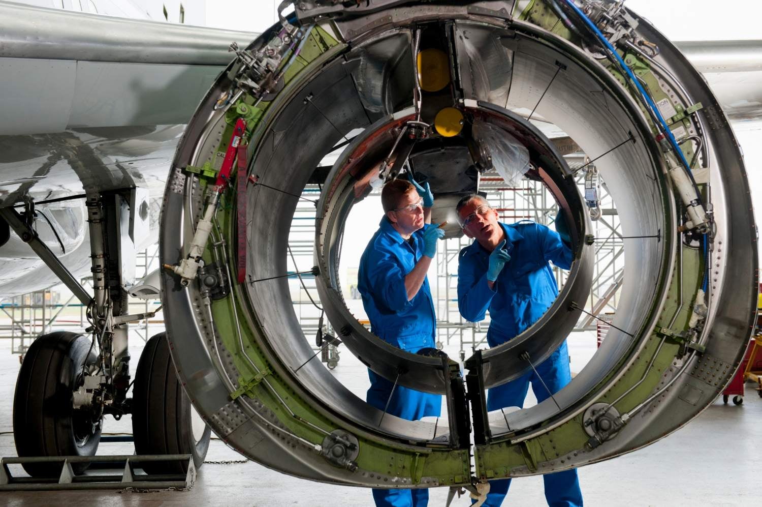 Two airplane technicians inspecting the plane's parts