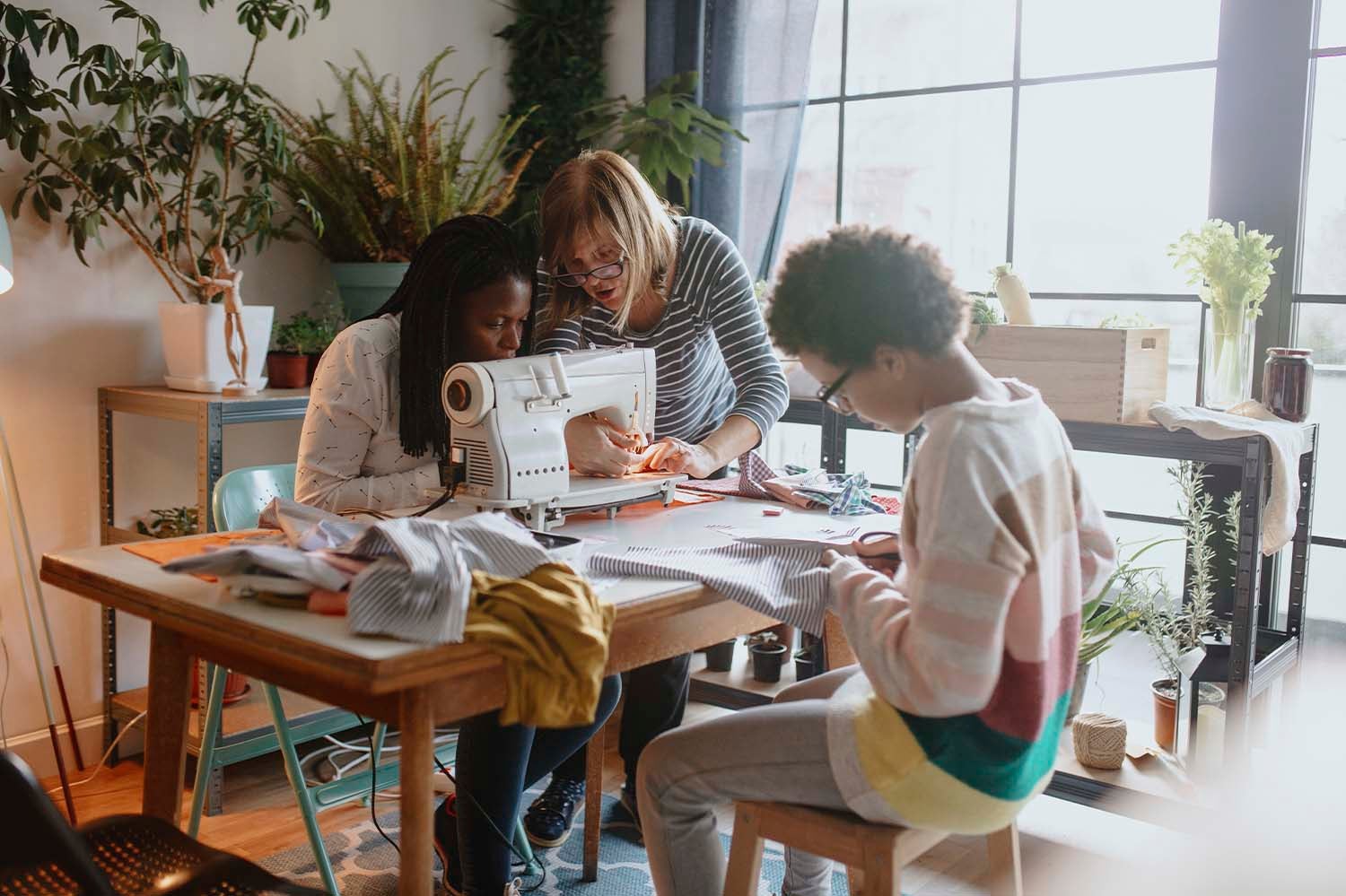 Three people sewing at a small table