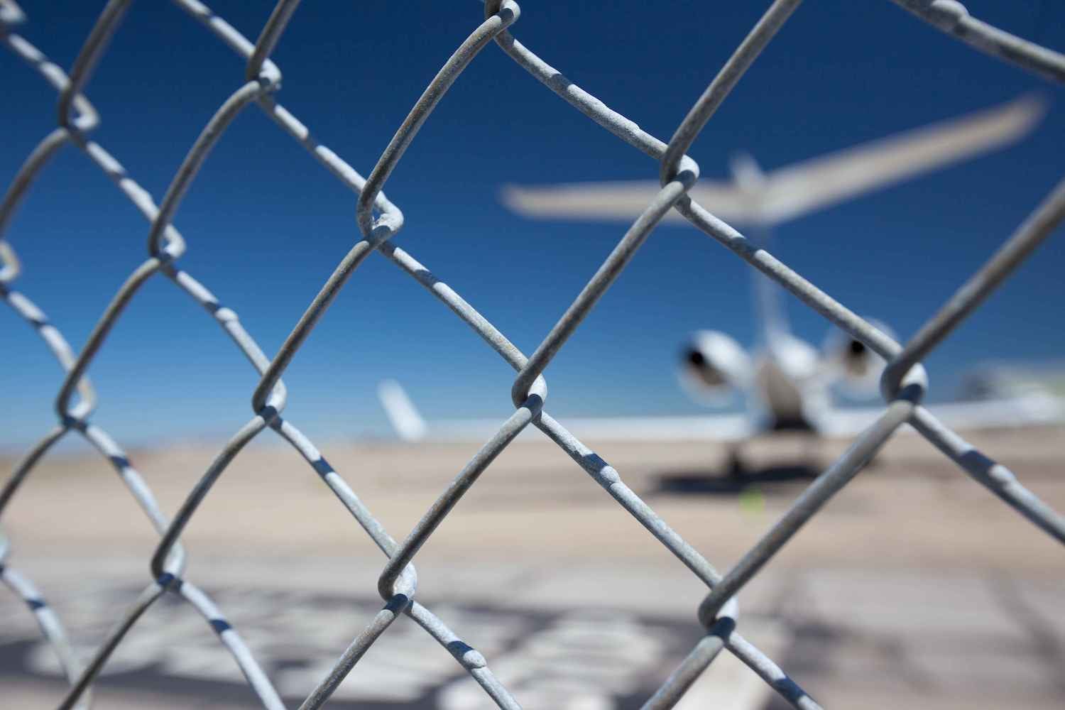 Chainlink fence with a plane in the background