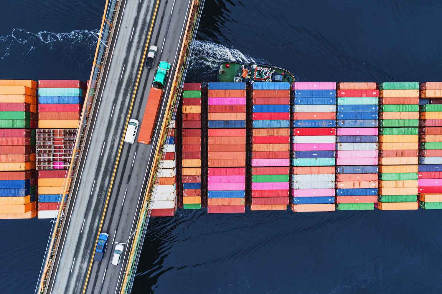 Overhead shot of a cargo ship passing under a road bridge