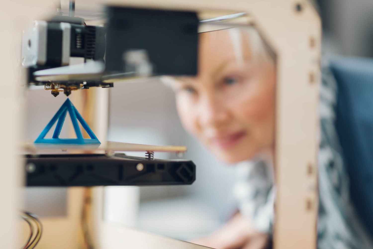 Woman watching a 3D printer produce a triangular form
