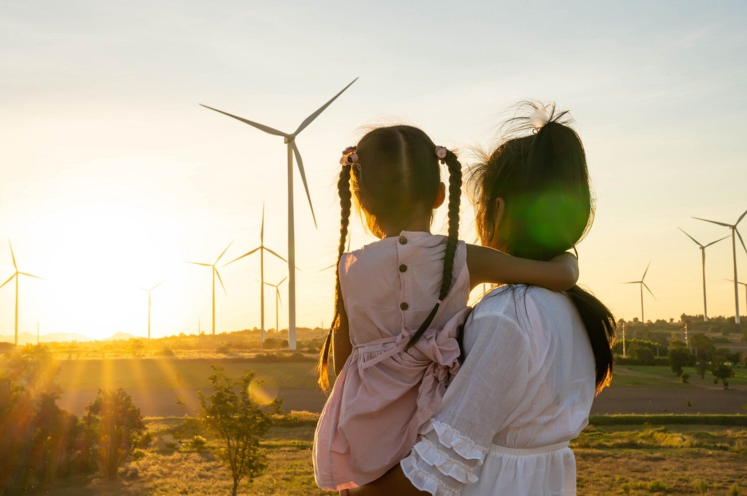 Mother and daughter looking at the sunset over a windmill farm