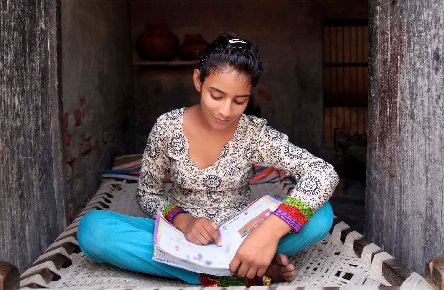 Child reading textbook in a small home