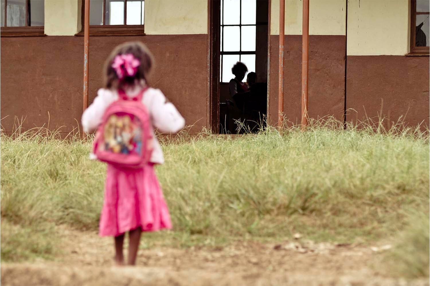 Child looking at rural school building