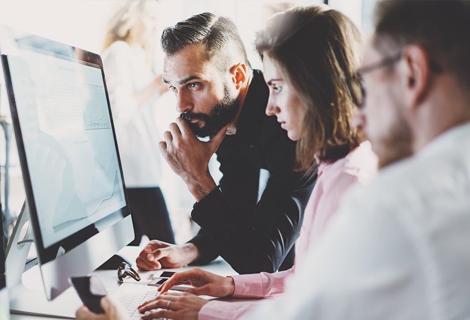 Three people working together at a computer