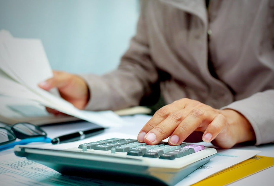 Close-up on a person's hands as they work on a calculator