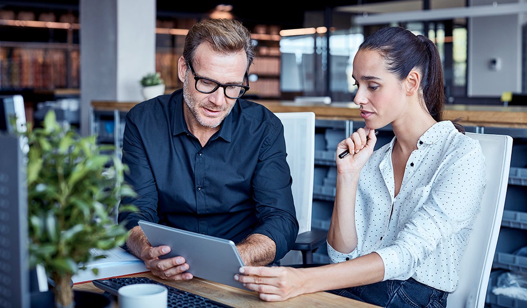 A man and a woman looking at a tablet.