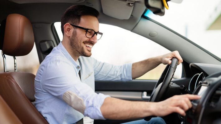 Smiling man driving a modern car, symbolizing confidence in his automotive supply chain compliance.