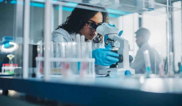 female scientist microscope testing chemicals lab