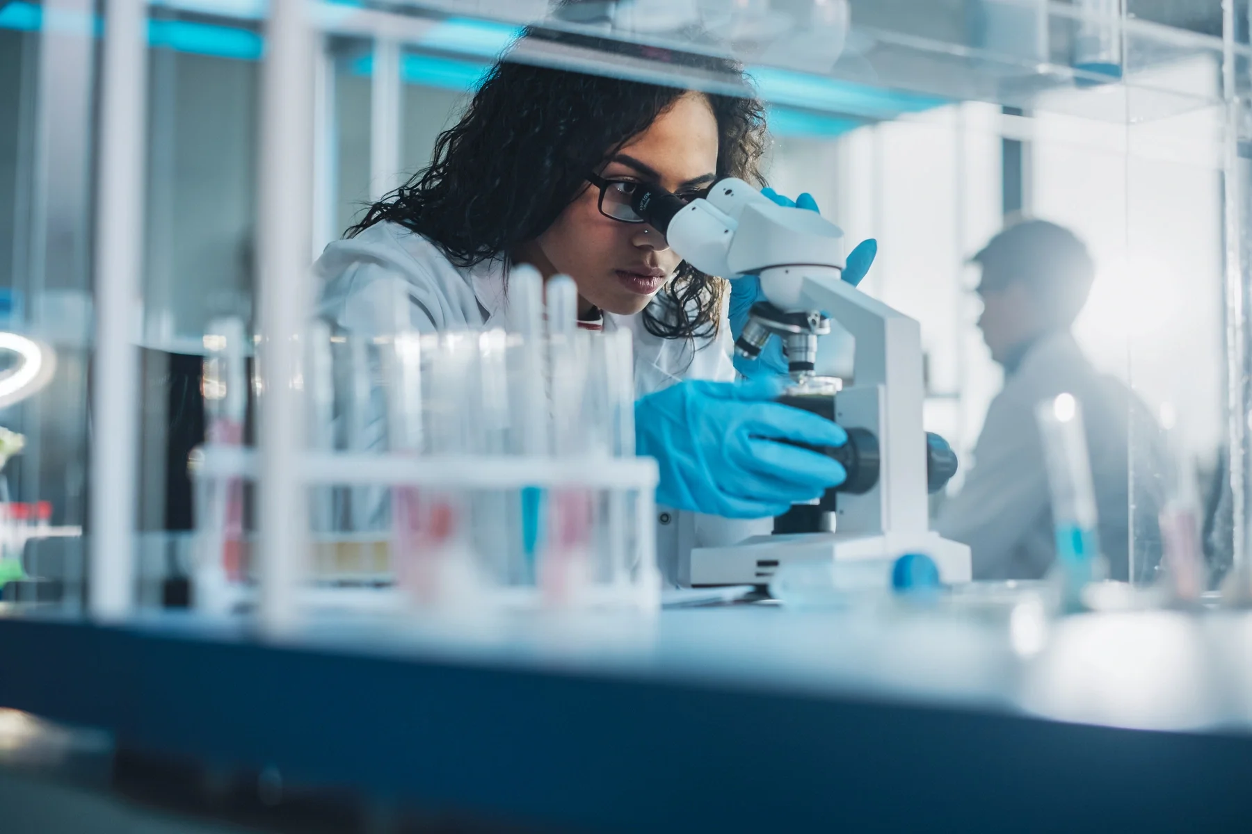 female scientist microscope testing chemicals lab
