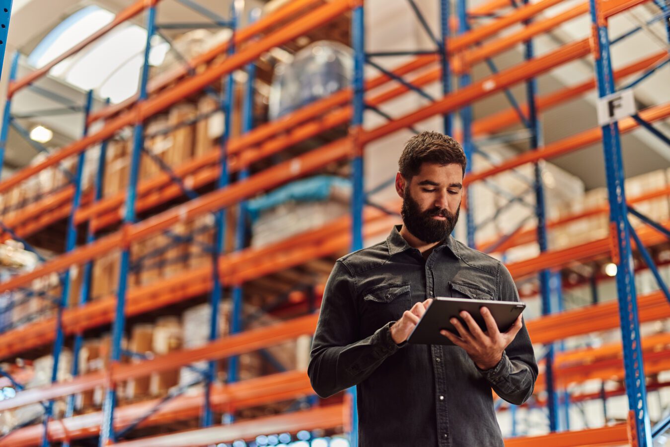 A male warehouse worker inspecting parts data on a tablet.