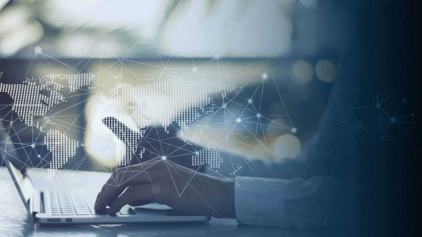 Person at a computer tapping into a global supply chain network.