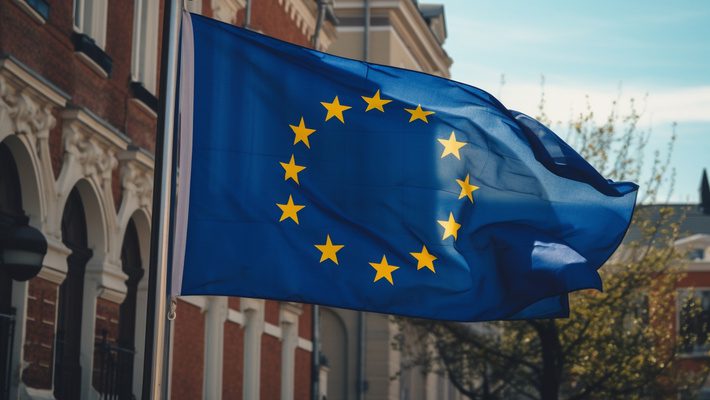 The European Union flag waving outside a building.